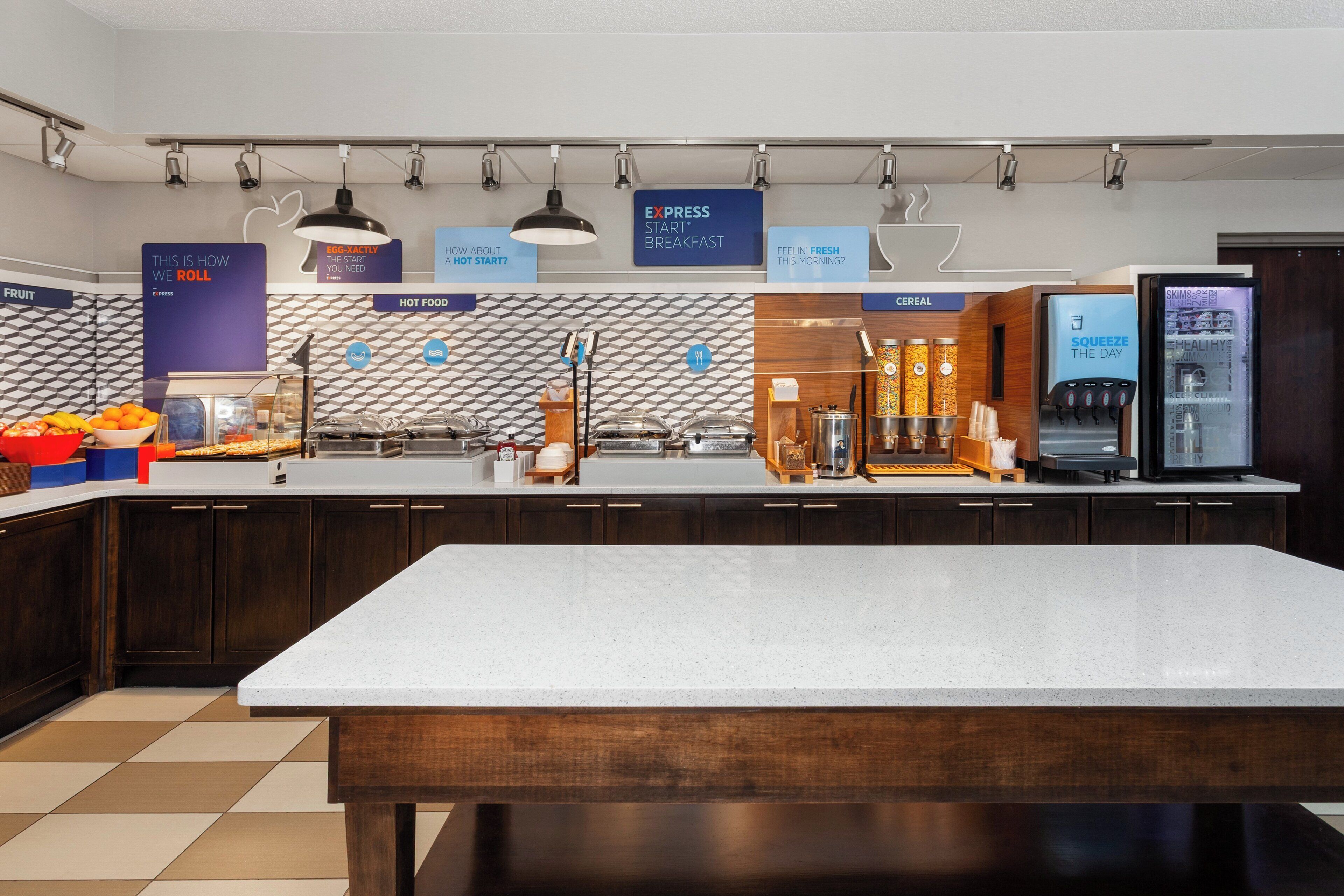 A modern breakfast area with a central island, breakfast bar, and various food and beverage dispensers.