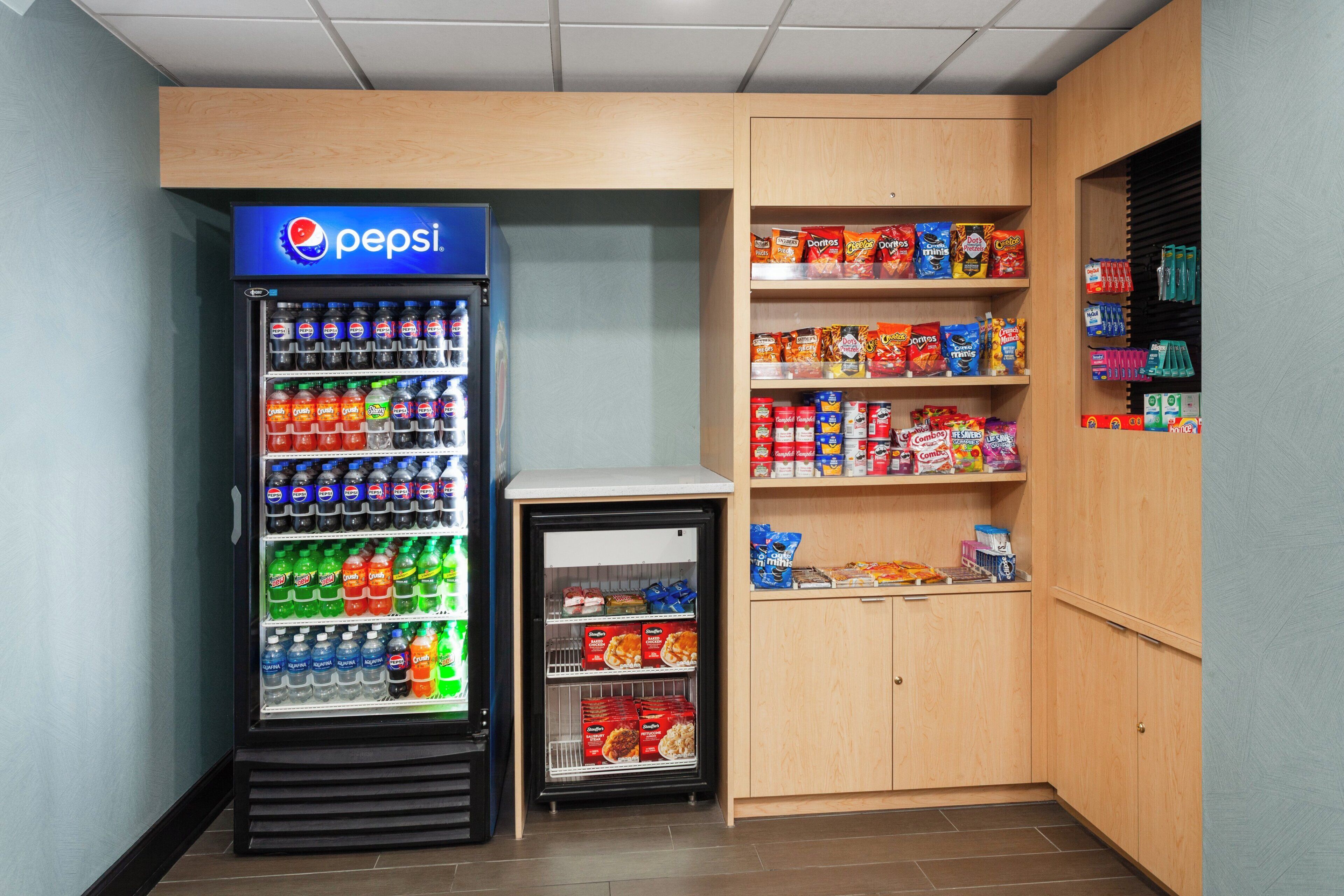 A vending machine with a Pepsi logo, surrounded by shelves stocked with snacks and beverages.