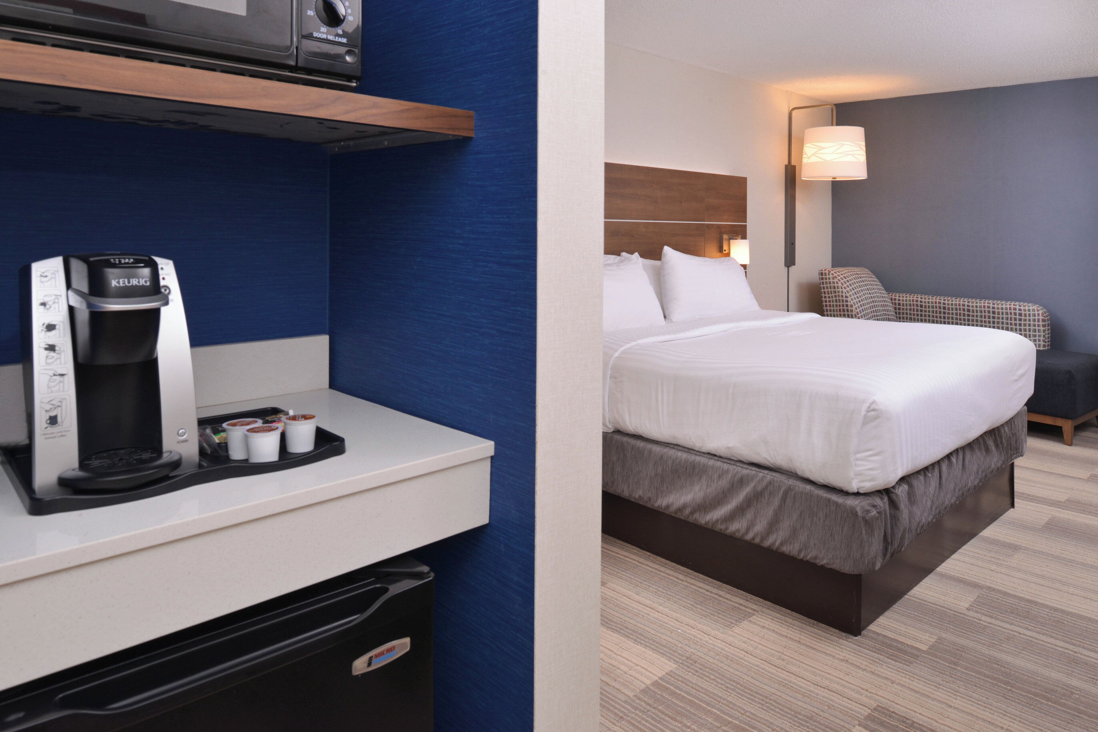 Una habitación de hotel con una cama, una cafetera y una pequeña mesa con tazas.