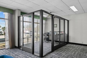 Un espacio de oficina moderno con un separador de vidrio, un escritorio con una silla y vistas al exterior.