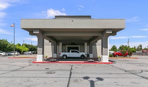 A building with a covered parking area, a white pickup truck parked inside, and a red car parked outside. - Quality Inn Cleveland, MS (Cleveland)