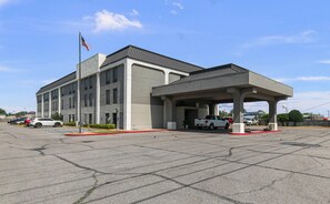 A building with a covered parking area, a flag, and a truck. - Quality Inn Cleveland, MS (Cleveland)