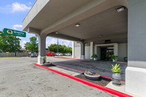 Entrada de un hotel con estacionamiento techado, un letrero de Quality Inn y un edificio con número 807.