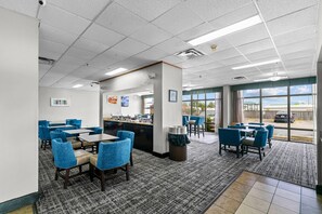 A hotel lobby with a reception desk, seating area, and large windows offering a view of the outdoors.