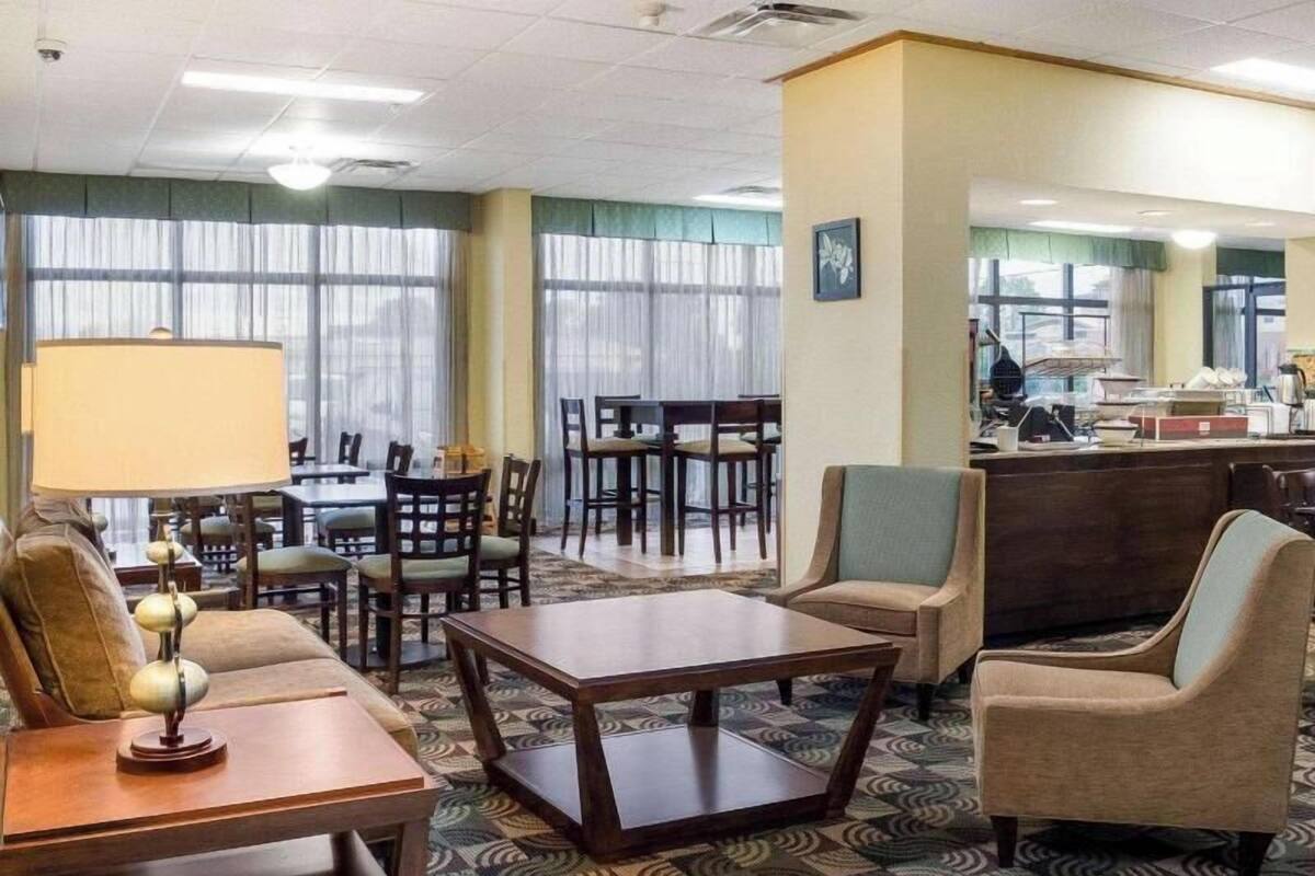 A hotel lobby with a dining area, a reception desk, and a seating area with a patterned carpet.