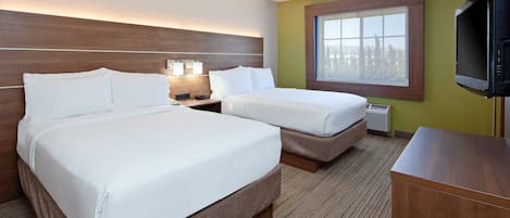 Habitación de hotel con dos camas, televisión, ventana y cabecero de madera.