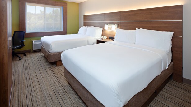 Une chambre d’hôtel avec deux lits, un bureau et une chaise.