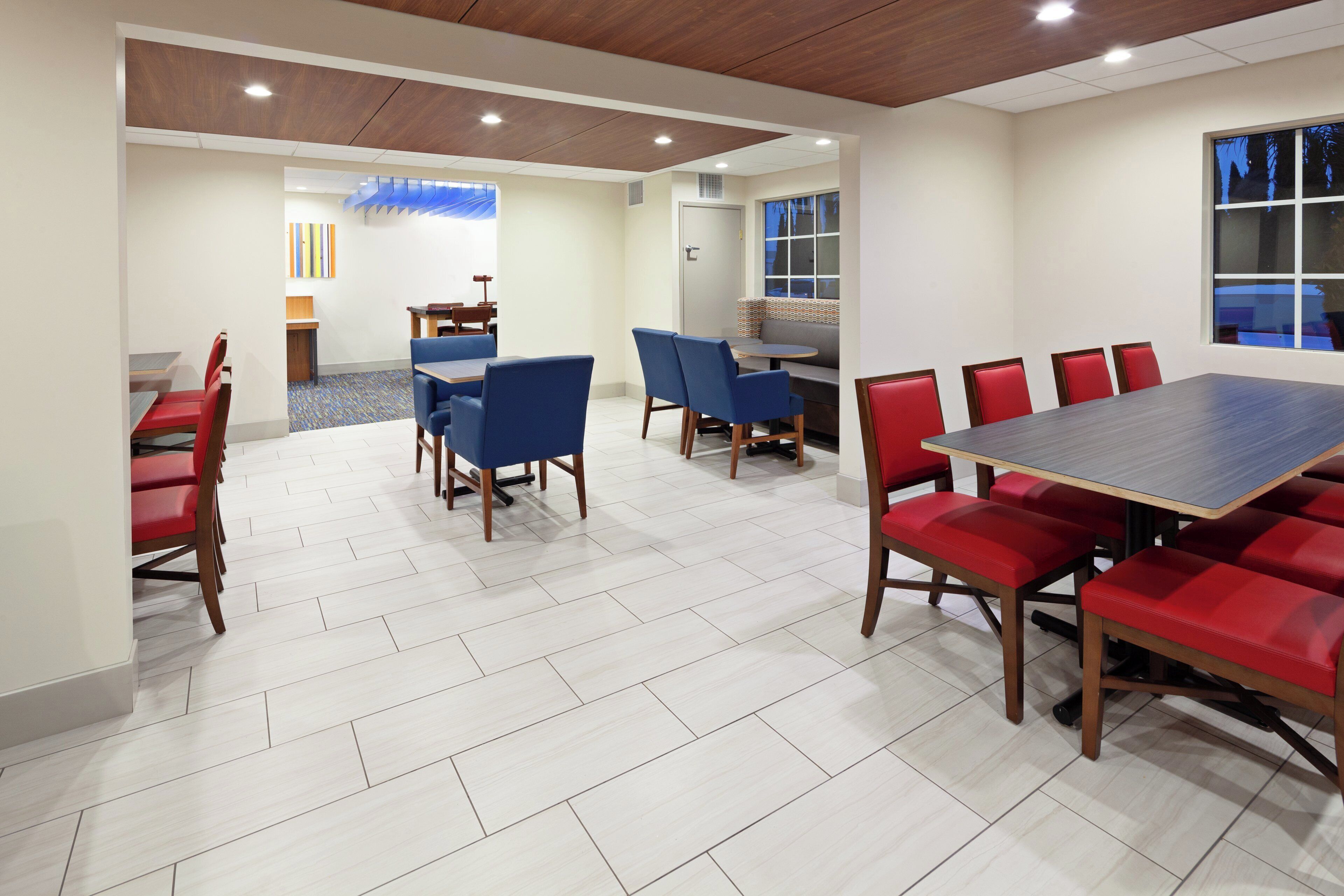 A conference room with a large table and chairs, a small seating area, and a window with a view.