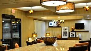 A hotel lobby with a marble reception desk, wooden paneling, and a television mounted on the wall. - Hampton Inn Sturgis-Lagrange Area (Sturgis)