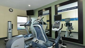 A gym with treadmills, elliptical machines, and a mirrored wall with motivational text.