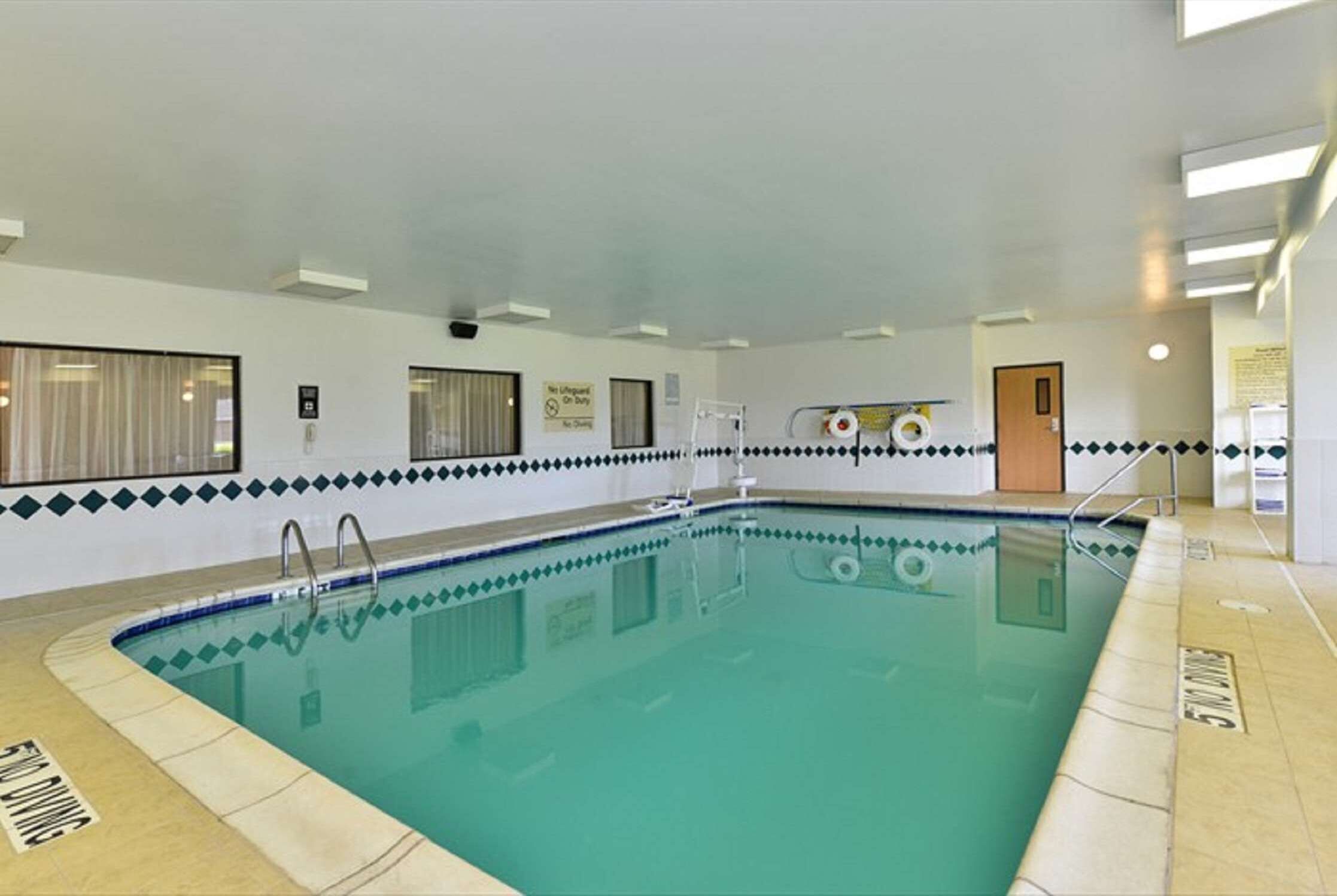 A swimming pool with a tiled border, a lifeguard chair, and a door in the background.