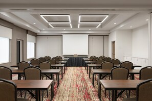 Une salle de conférence avec une longue table, des chaises, un écran de projection et un sol recouvert de moquette.