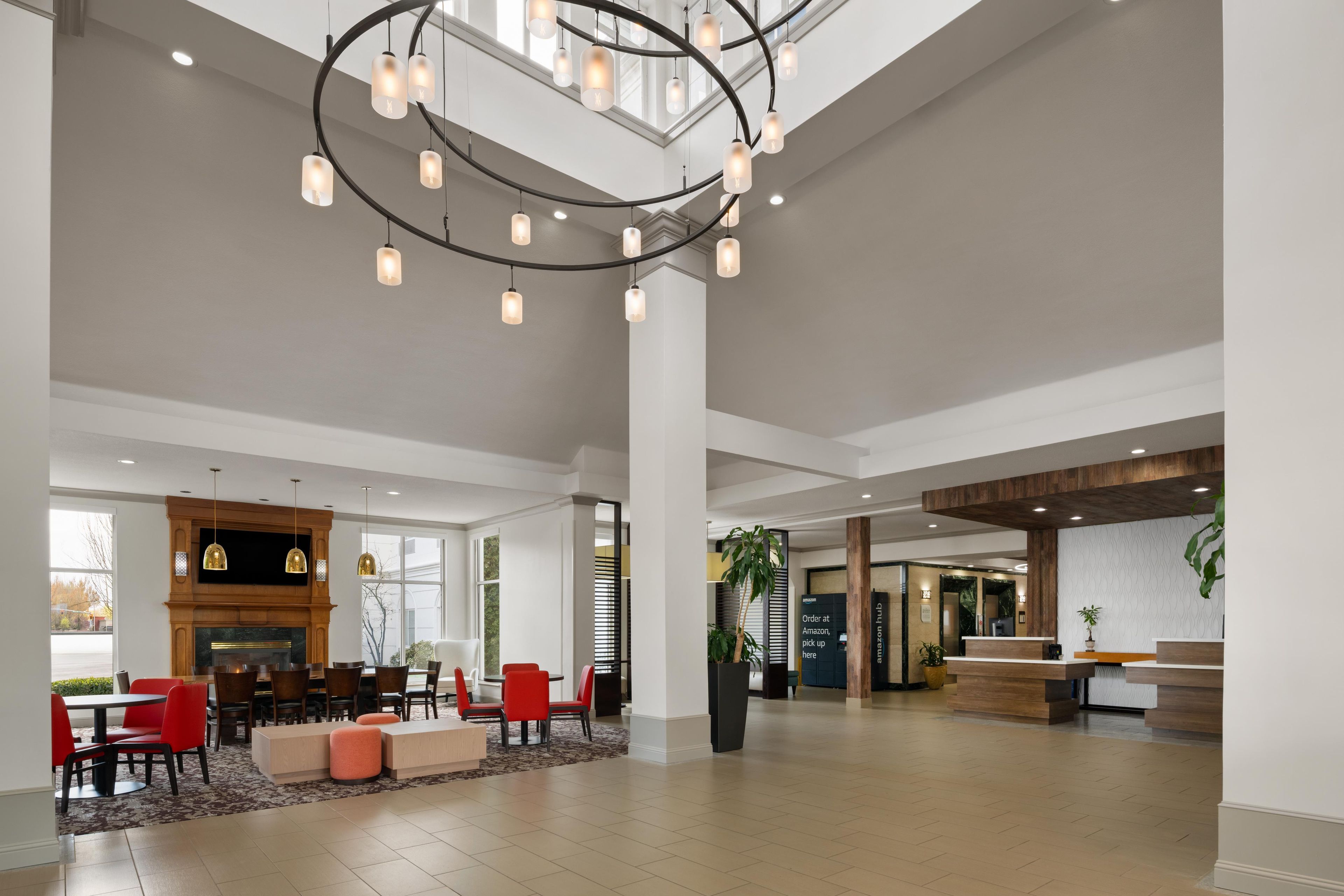 A spacious lobby with a modern chandelier, a fireplace, and a reception desk.