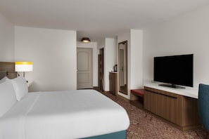 A hotel room with a bed, a television, a desk, and a mirror.