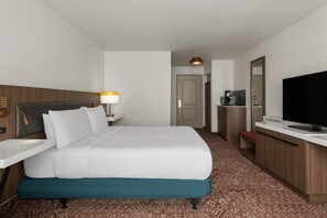 A hotel room with a bed, bedside table, lamp, television, and a small kitchenette area. - Hilton Garden Inn Portland Airport (Portland)
