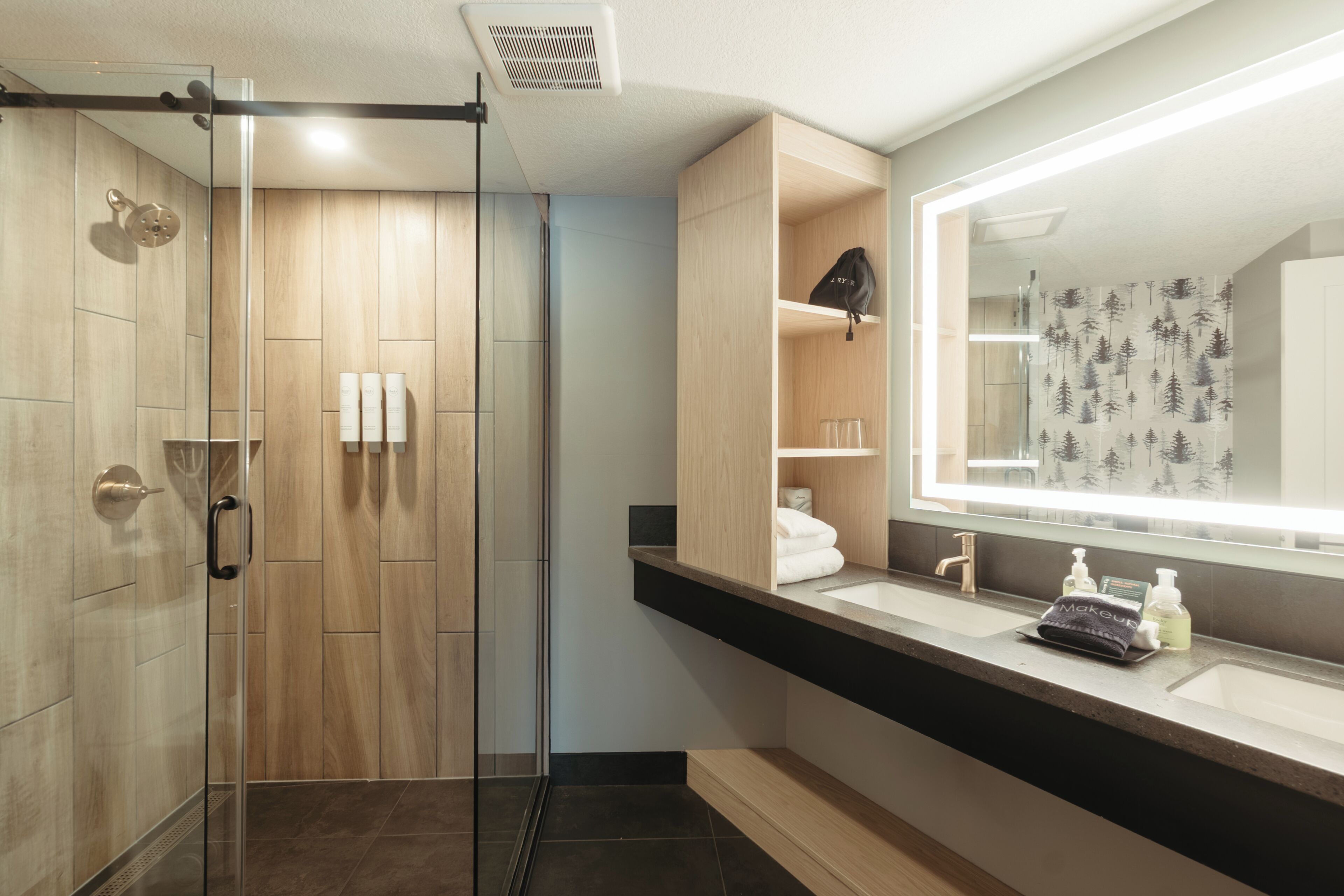 A modern bathroom with a glass shower enclosure, a large mirror, and a vanity with a sink.