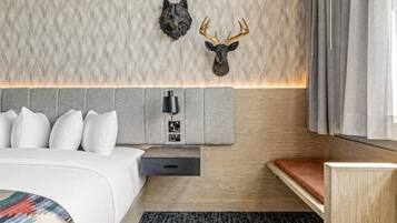 A modern hotel room with a bed, a nightstand, a lamp, and a headboard with wall-mounted decor.