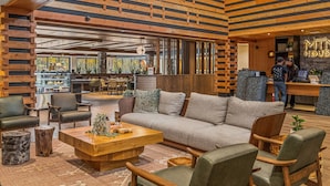 Un intérieur moderne avec un plafond à lattes de bois, un comptoir d’accueil et un espace détente comprenant un canapé et des fauteuils.