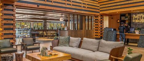 A modern interior with a wooden slatted ceiling, a reception desk, and a seating area with a sofa and chairs.