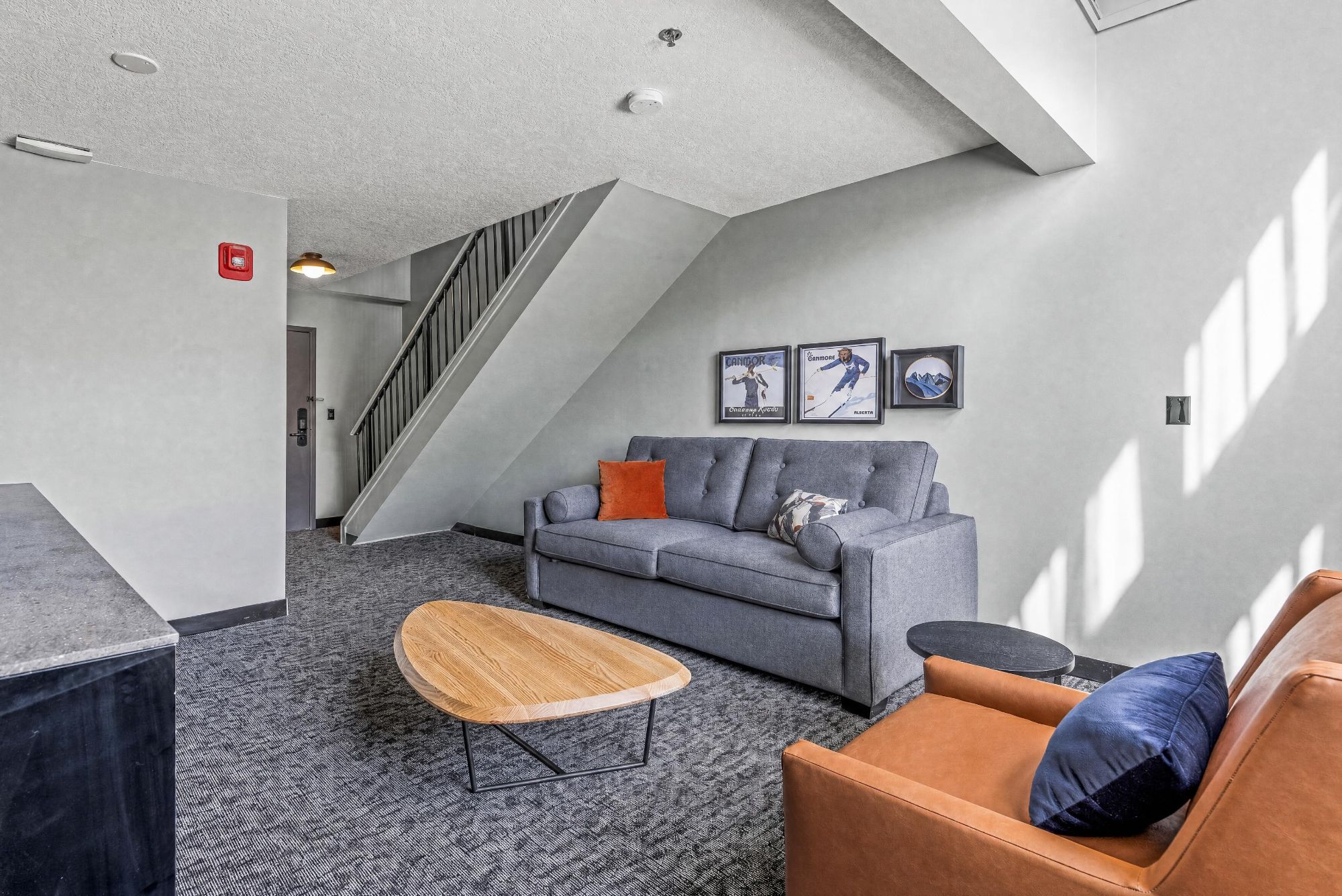 A modern interior with a grey sofa, a wooden coffee table, and a staircase.