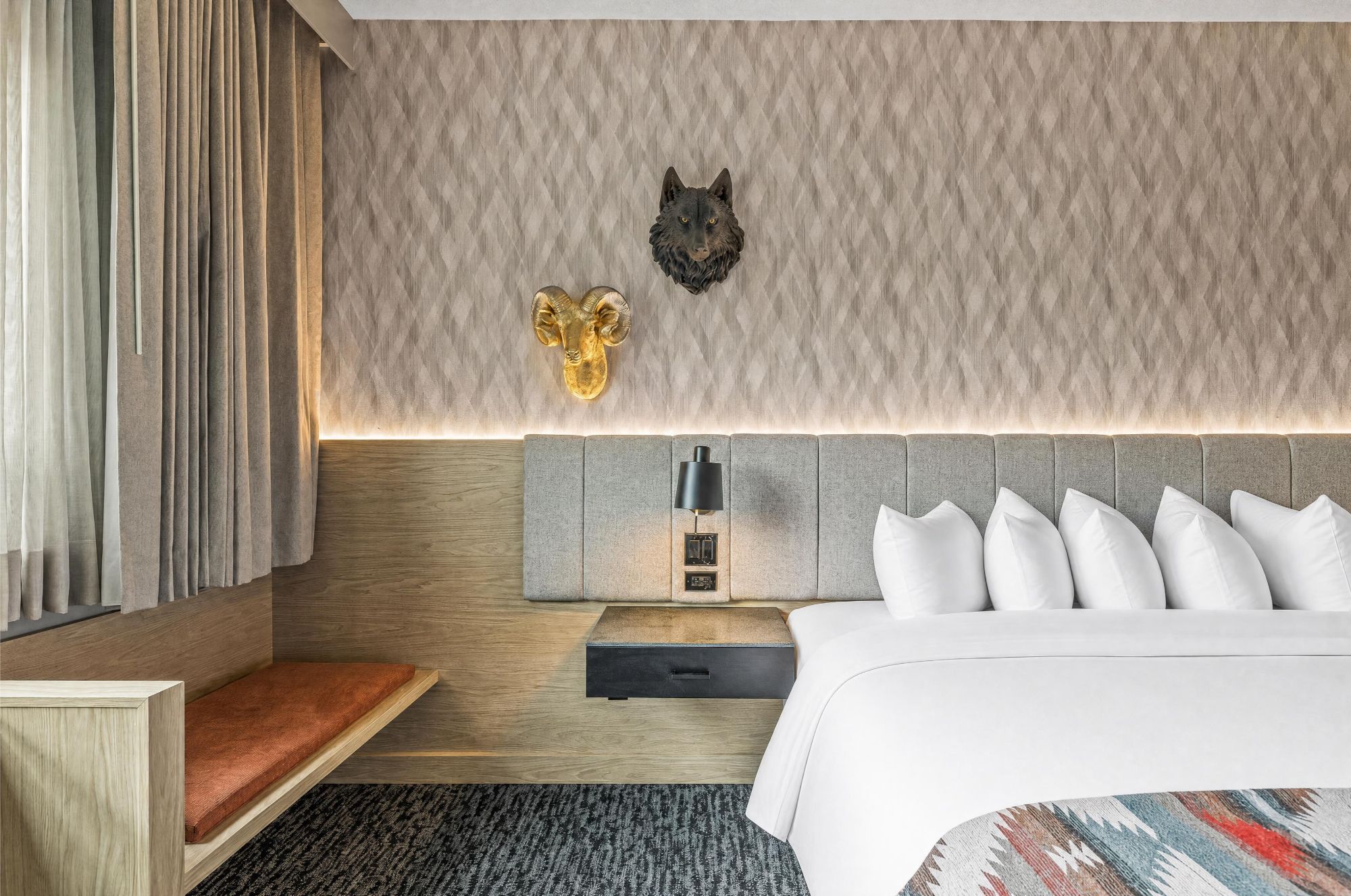 A hotel room with a bed, a nightstand, a lamp, and wall-mounted decor.