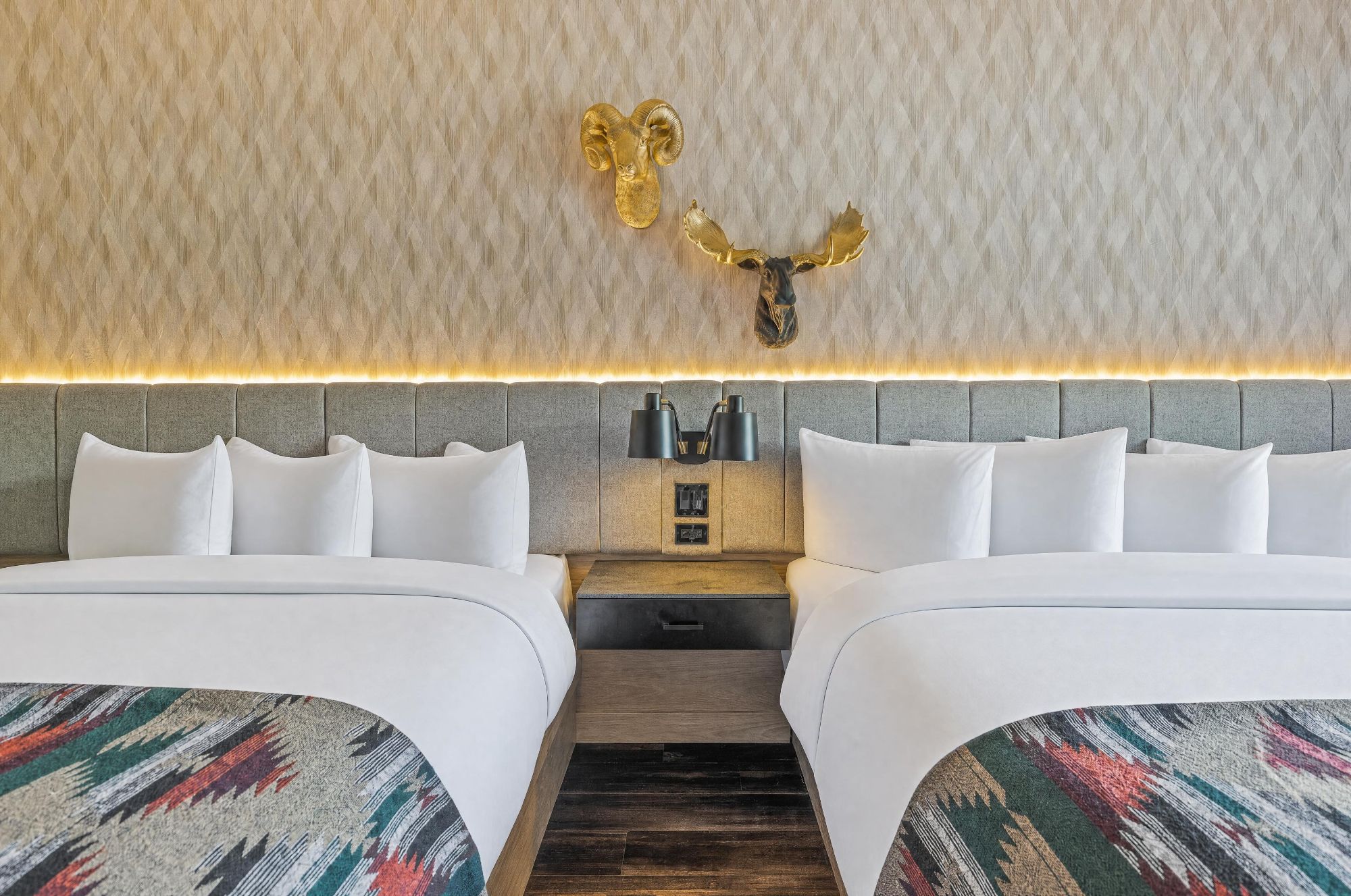 Una habitación de hotel con dos camas, un cabecero con panel iluminado y un adorno en la pared.