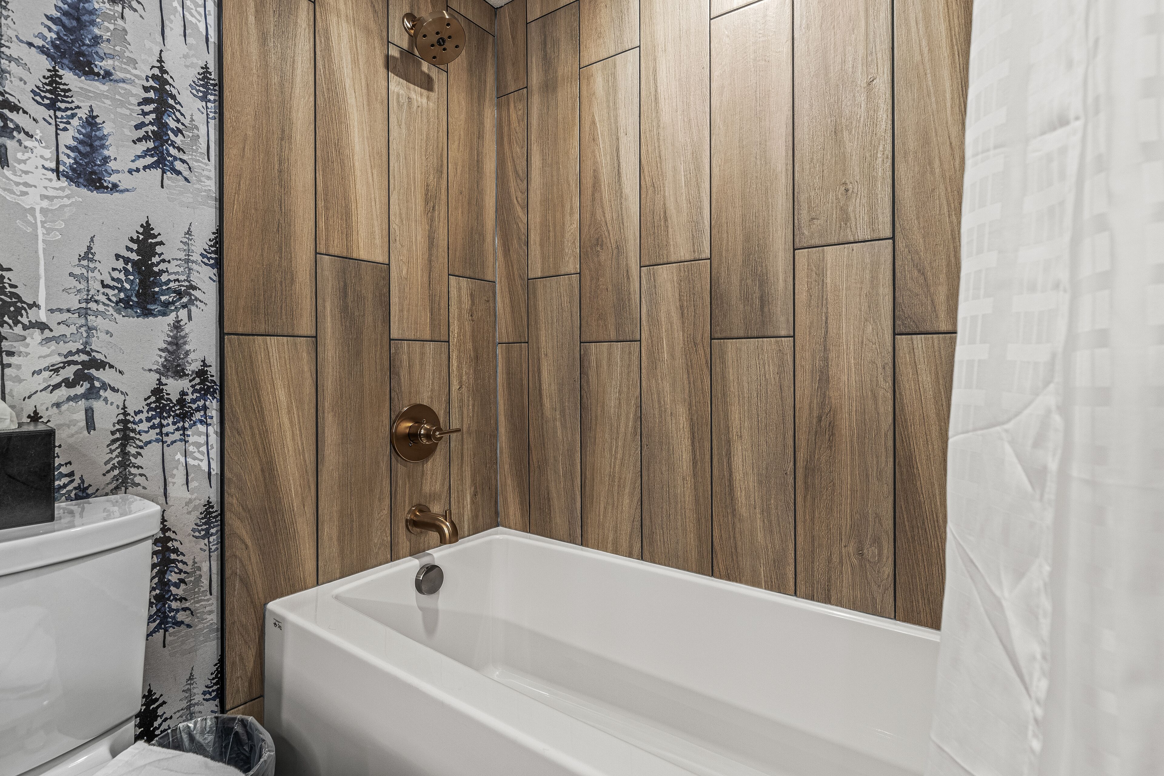 Ein Badezimmer mit Holzwand, einer Badewanne und einer Dusche mit Regendusche.