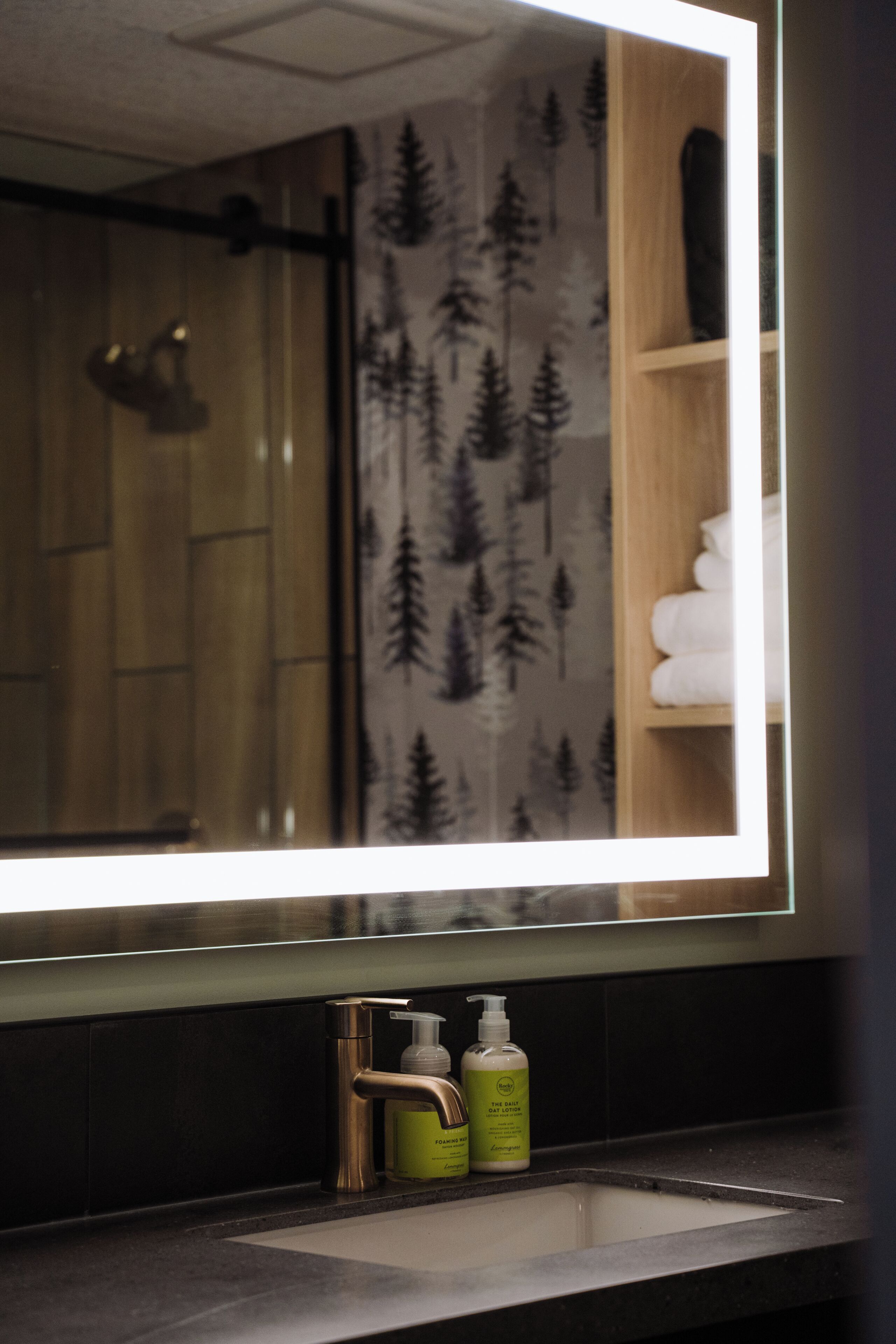 A bathroom with a large mirror, a sink, and two bottles of soap.