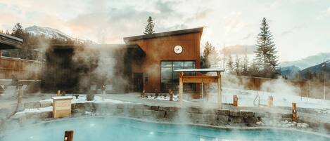 A modern building with a pool, surrounded by steam vents and a mountainous backdrop.