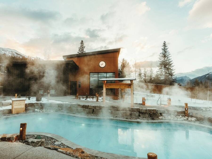 A modern building with a pool, surrounded by steam vents and a mountainous backdrop.