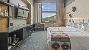 Une chambre d’hôtel moderne dotée d’un grand lit, d’un bureau et d’une fenêtre donnant sur un paysage pittoresque.