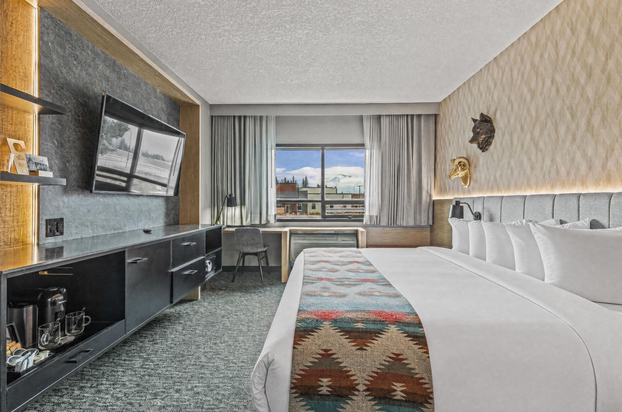 A hotel room with a bed, a desk, a chair, a television, and a window with a view of the outside.