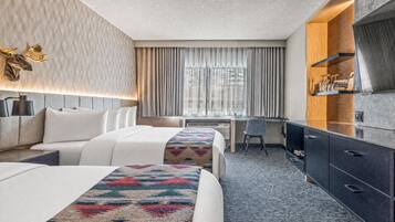 Habitación de hotel con dos camas, un escritorio, una silla y un televisor.