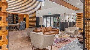 Un hall d’entrée spacieux au design moderne, comprenant un canapé en cuir, des fauteuils et une table basse.