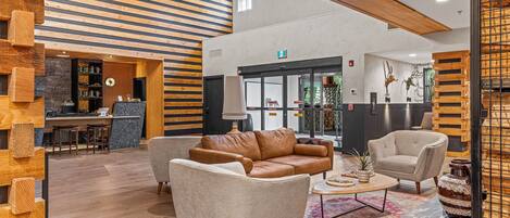 A spacious lobby with a modern design, featuring a leather sofa, armchairs, and a coffee table.