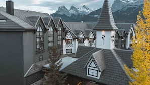 Une rangée de bâtiments de style chalet, avec des toits pentus et des fenêtres en lucarne, se dressant sur fond de montagnes enneigées.