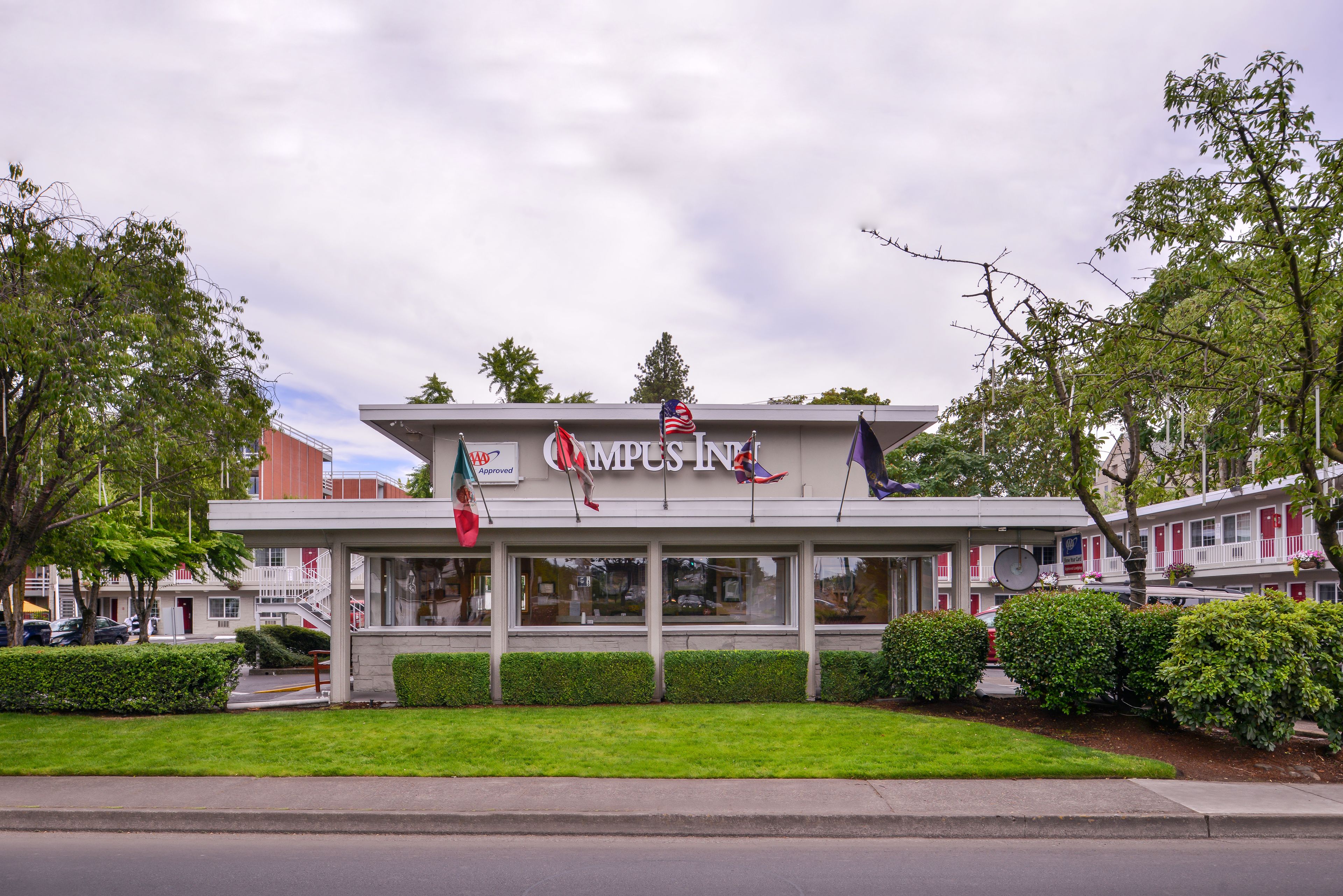 A building with a sign reading "Campsite Inn" and multiple flags, including the American flag, on the roof.