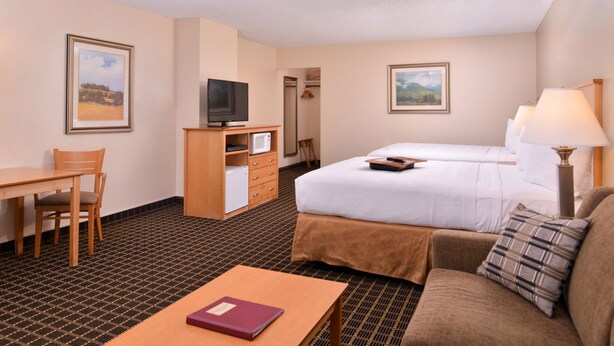 Una habitación de hotel con cama, sofá, escritorio, televisor y espejo.