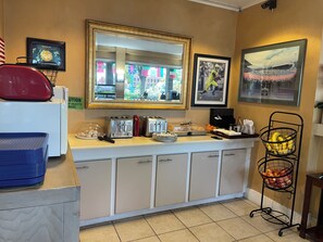 A hotel reception area with a counter, a mirror, framed pictures, and a fruit basket. - Campus Inn & Suites Eugene Downtown (Eugene)