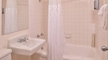 A bathroom with a sink, mirror, shower curtain, and a towel rack.