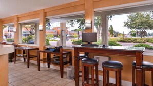Un área de bar con taburetes de madera, una computadora y vista a la calle.