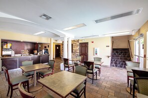 A restaurant with a bar area, multiple tables and chairs, a staircase, and a stone wall. - Red Roof Inn San Marcos (San Marcos)