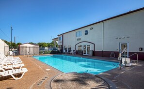 Una piscina al aire libre, sombrillas, sillones reclinables de piscina