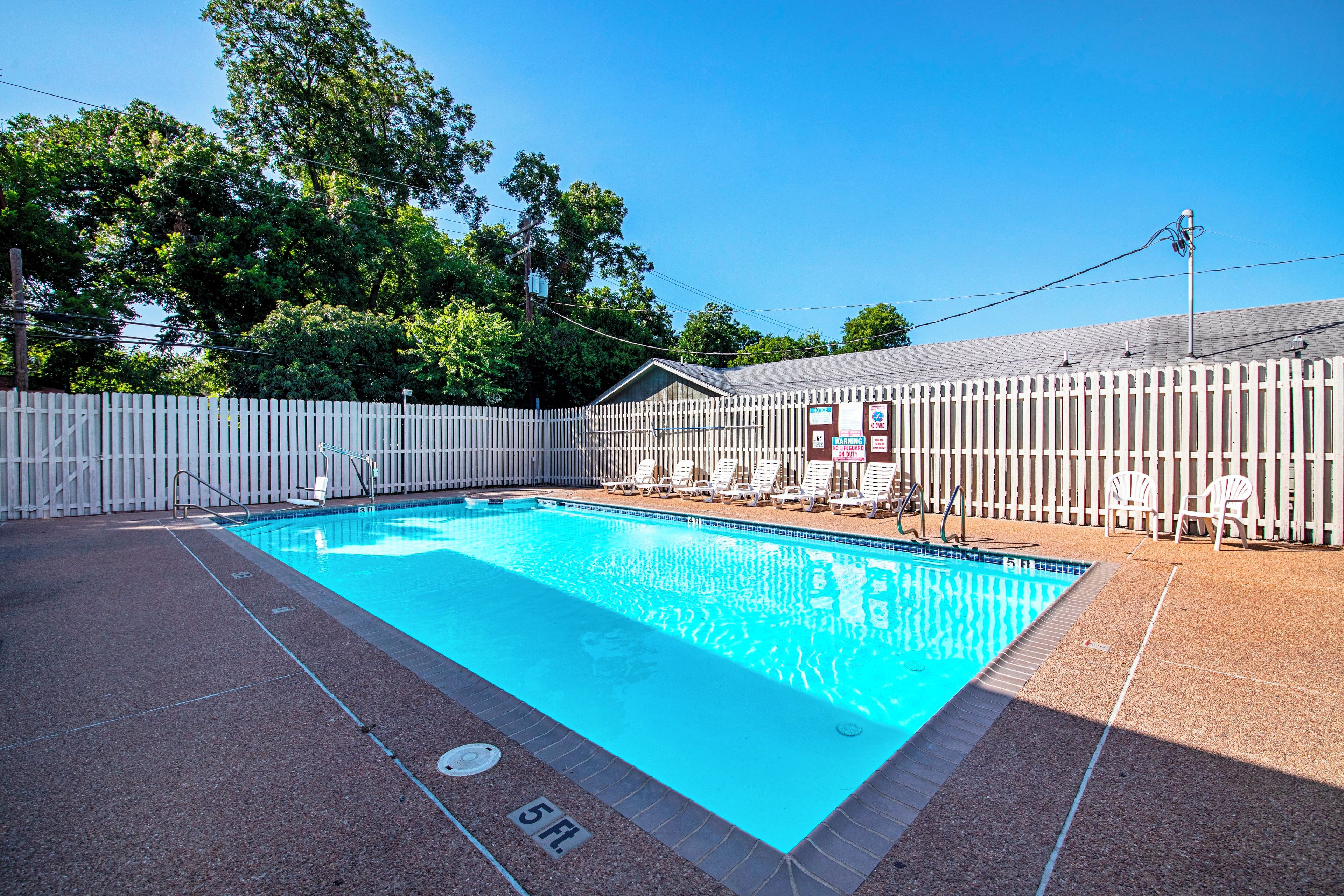 Una piscina al aire libre, sombrillas, sillones reclinables de piscina