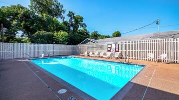 Una piscina al aire libre, sombrillas, sillones reclinables de piscina