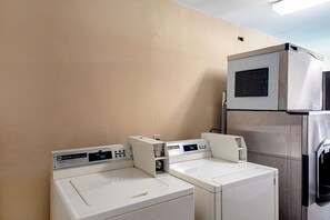 A laundry area with two white washing machines and a stainless steel dryer. - Red Roof Inn San Marcos (San Marcos)