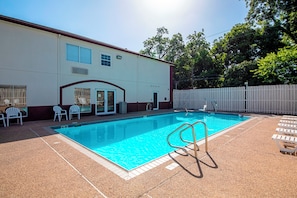 A swimming pool with a clear blue water, surrounded by a white fence, and a building with a red roof and windows. - Red Roof Inn San Marcos (San Marcos)