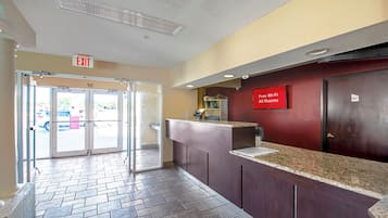 A hotel reception area with a glass door entrance, a reception desk, and a sign indicating free Wi-Fi in all rooms.