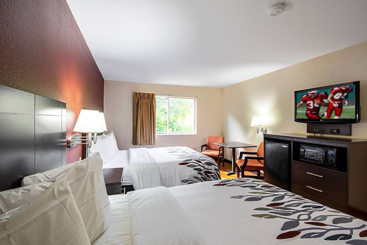 Une chambre d’hôtel avec deux lits, une télévision, un bureau et une fenêtre.