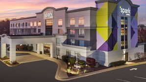 A hotel with a modern design, featuring a prominent 'spark by Hilton' sign, a well-lit entrance, and a landscaped front yard.